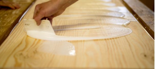 man applying adhesive glue to wood